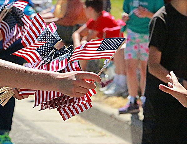 people passing out american flags at parade